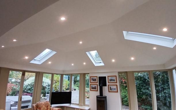 A finished conservatory roof conversion from inside: a plastered, painted ceiling with rooflights and downlights