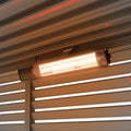 Nova Hestia 2kW infrared heater mounted under a pergola roof, element glowing at dusk