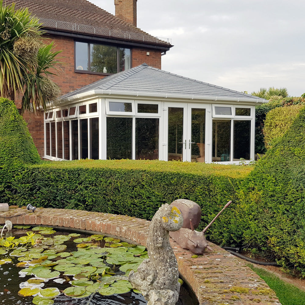A house with a new tiled conservatory roof, seen across the garden
