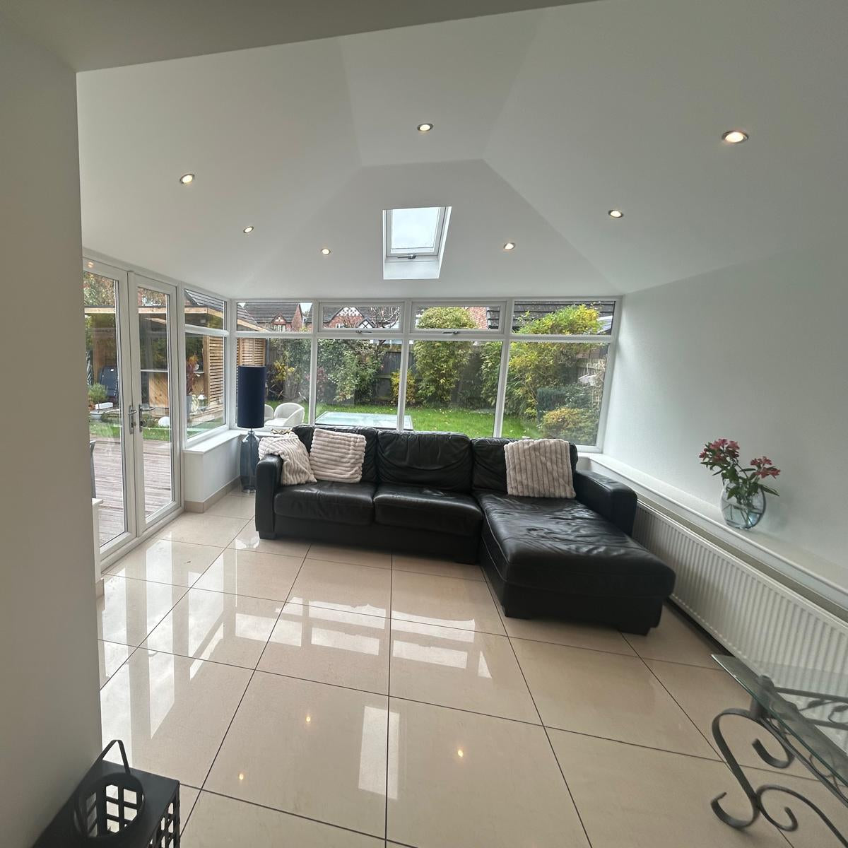 The inside of a converted conservatory, with a plastered ceiling and downlights