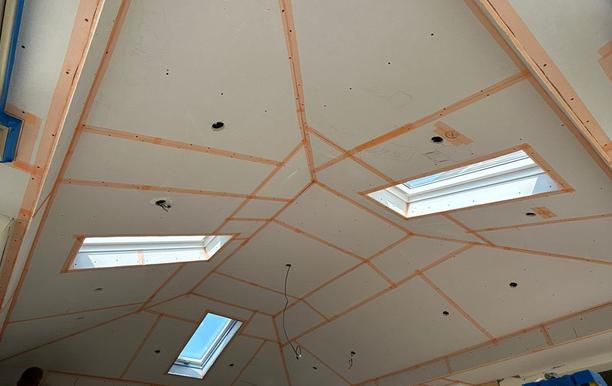 Plasterboard fixed to the underside of a conservatory roof with the joints taped and the rooflight openings cut, before the skim